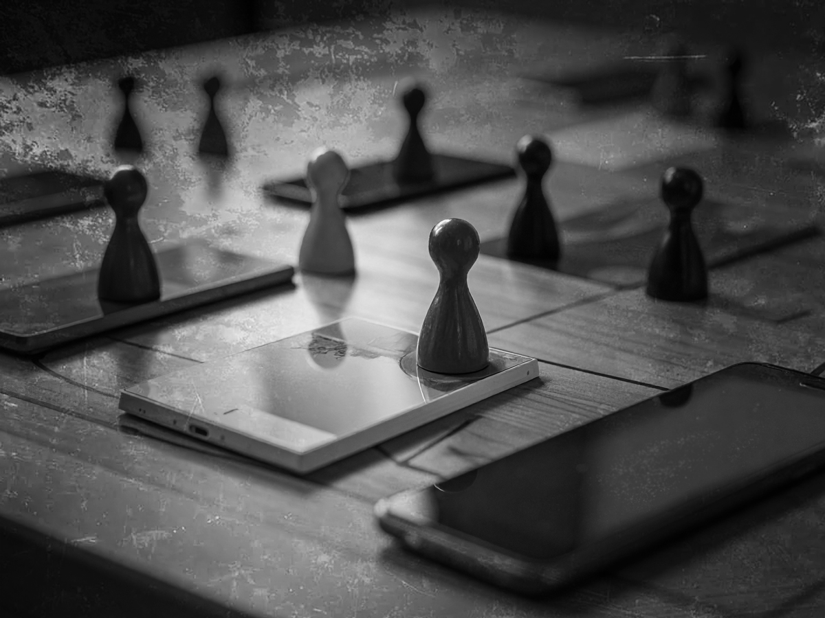 Smart phones and tablets scattered across a game board, seen through a dark filter